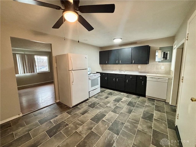 kitchen featuring white appliances, a sink, decorative backsplash, light countertops, and dark cabinets