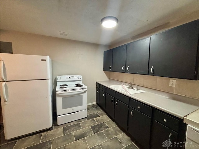 kitchen with dark cabinetry, white appliances, a sink, light countertops, and tasteful backsplash