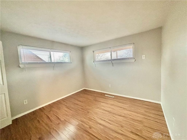 spare room featuring baseboards and wood finished floors