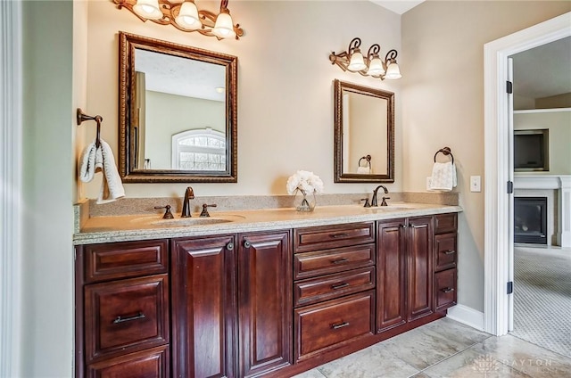 full bath featuring double vanity, a fireplace, and a sink