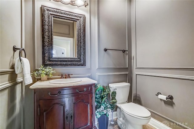 half bathroom with toilet, a decorative wall, and vanity