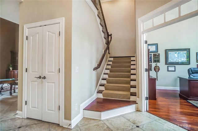 stairway with baseboards and tile patterned floors