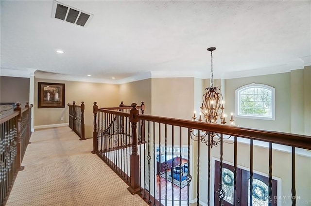 hallway featuring a chandelier, light colored carpet, an upstairs landing, visible vents, and ornamental molding