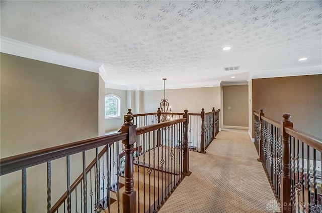 corridor with visible vents, ornamental molding, light carpet, a textured ceiling, and an upstairs landing