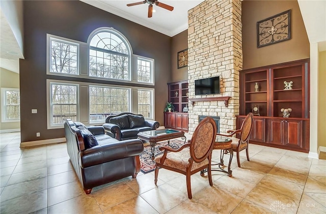 living area featuring a high ceiling, baseboards, crown molding, and a stone fireplace