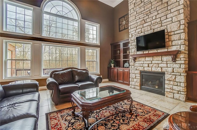 living area with tile patterned floors, a high ceiling, baseboards, and a stone fireplace