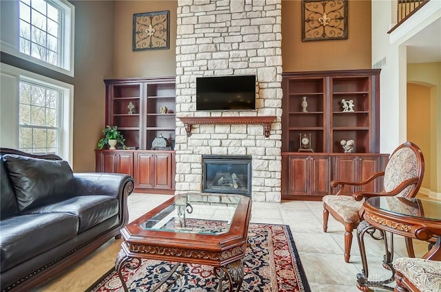 living area featuring light tile patterned floors, a fireplace, and a towering ceiling