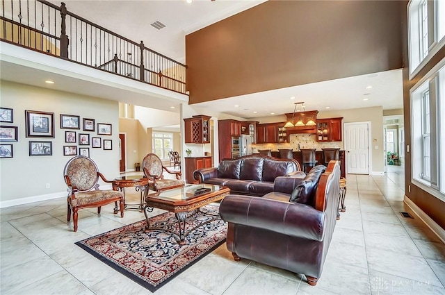 living room with a towering ceiling, baseboards, and visible vents