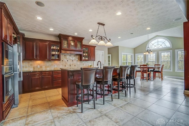 kitchen featuring stainless steel appliances, reddish brown cabinets, decorative backsplash, and a kitchen bar