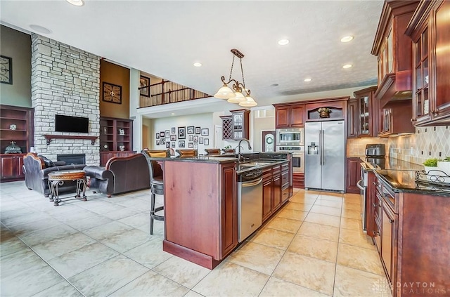 kitchen featuring a breakfast bar area, stainless steel appliances, open floor plan, a sink, and dark brown cabinets