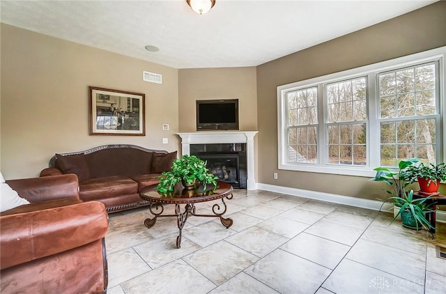 living room with visible vents, baseboards, a tiled fireplace, and tile patterned floors