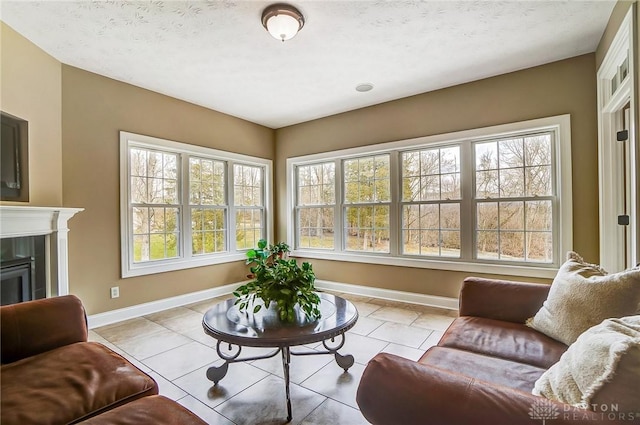 tiled living room with a textured ceiling, a fireplace, and baseboards