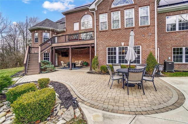 rear view of property with brick siding, stairway, and a patio