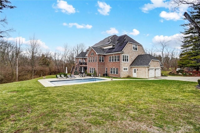 rear view of house featuring a patio, a lawn, an attached garage, an outdoor pool, and driveway