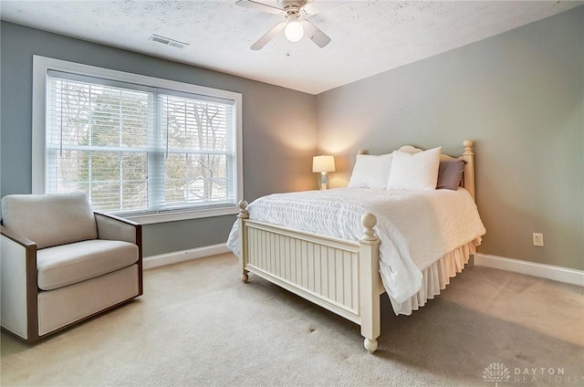 carpeted bedroom with a textured ceiling, ceiling fan, visible vents, and baseboards