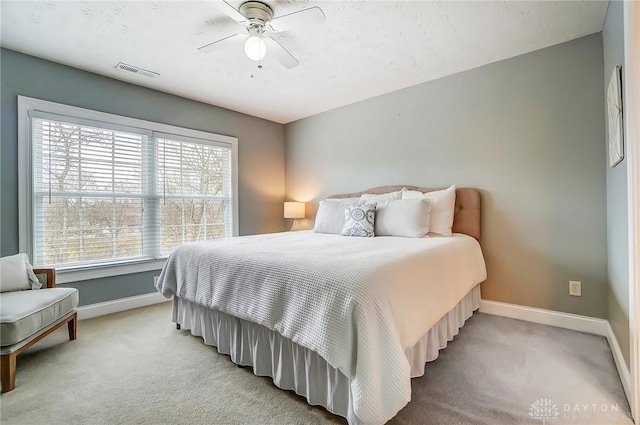 bedroom featuring light colored carpet, ceiling fan, visible vents, and baseboards