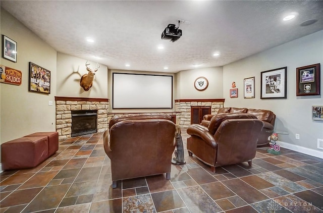 cinema room featuring recessed lighting, a stone fireplace, and baseboards