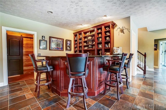 bar with baseboards, stairway, a dry bar, and a textured ceiling