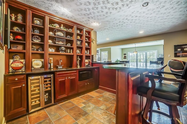 bar with a textured ceiling, recessed lighting, beverage cooler, a sink, and indoor wet bar