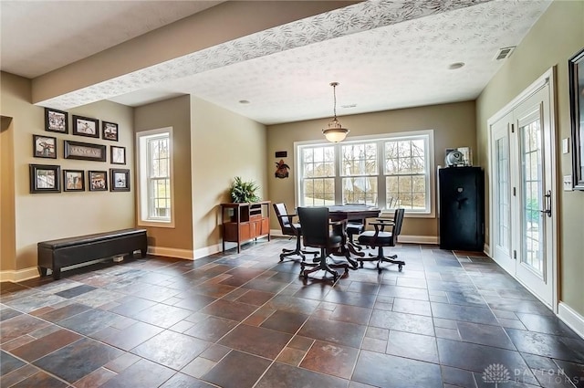 dining area featuring stone finish flooring, visible vents, a textured ceiling, and baseboards