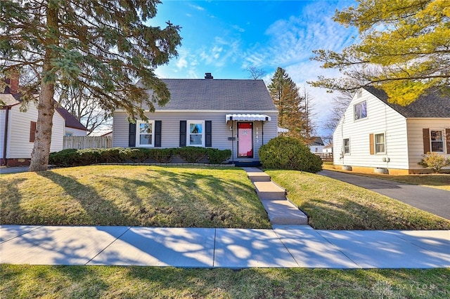 view of front of home featuring fence, a front lawn, and roof with shingles