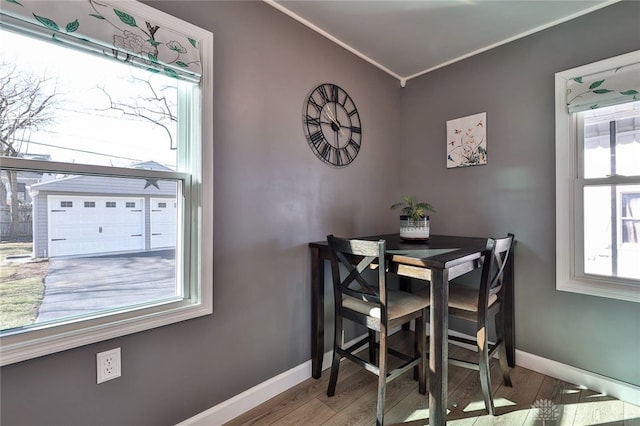 dining space featuring ornamental molding, baseboards, and wood finished floors