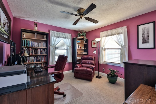 carpeted office space with ceiling fan, a textured ceiling, baseboards, and a wealth of natural light