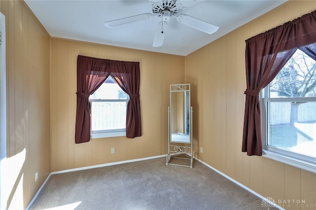 carpeted empty room with ceiling fan and baseboards