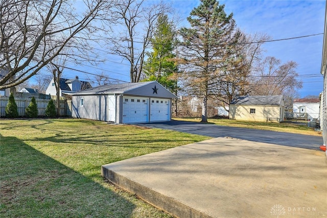 view of yard featuring an outbuilding, a detached garage, and fence