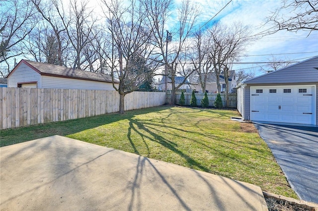 view of yard featuring a garage, a fenced backyard, a patio, and driveway