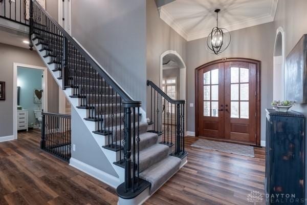 entrance foyer with arched walkways, french doors, baseboards, and wood finished floors