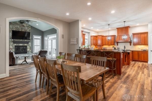 dining area featuring vaulted ceiling, recessed lighting, a fireplace, and dark wood-style flooring