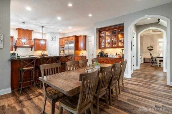 dining space with recessed lighting, arched walkways, dark wood-style flooring, and baseboards