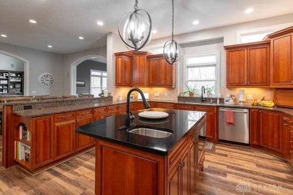 kitchen featuring a sink, plenty of natural light, stainless steel dishwasher, and a center island with sink