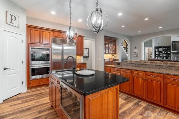 kitchen with brown cabinetry, recessed lighting, wood finished floors, and built in appliances