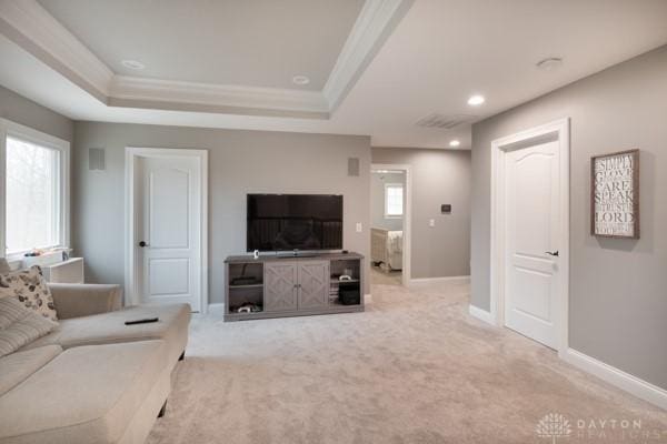 living area featuring crown molding, a raised ceiling, and baseboards