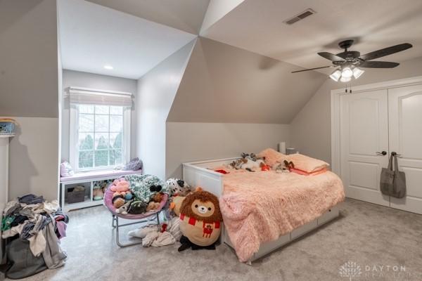 carpeted bedroom with visible vents, a closet, a ceiling fan, and vaulted ceiling