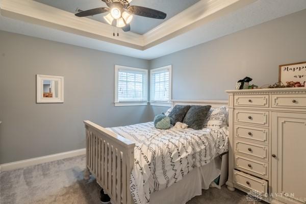 bedroom with a raised ceiling, baseboards, dark colored carpet, and ceiling fan