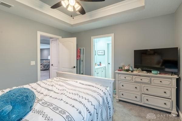 carpeted bedroom featuring ceiling fan, visible vents, a raised ceiling, and connected bathroom