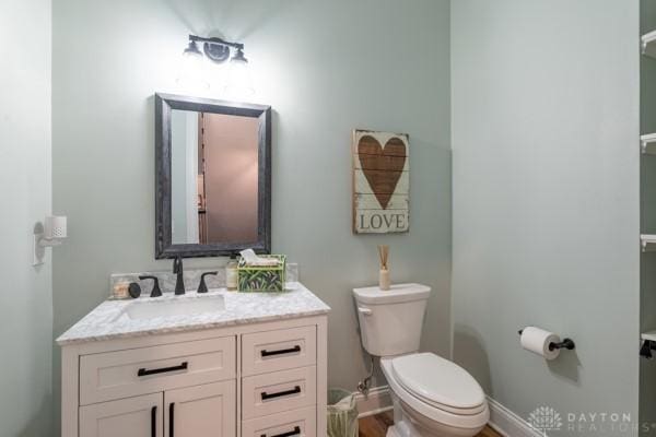 bathroom with toilet, vanity, and baseboards