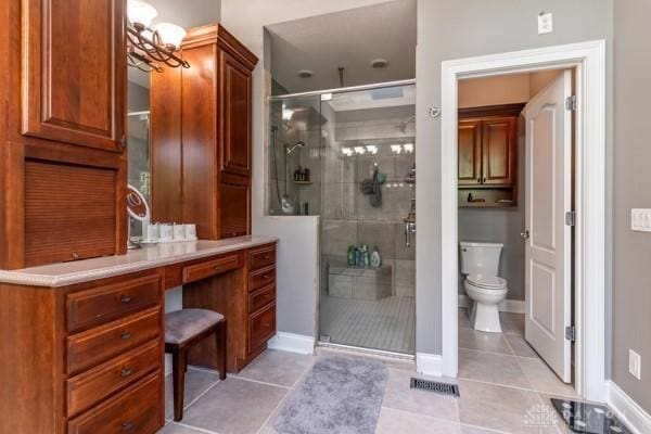 full bath with an inviting chandelier, a shower stall, toilet, and tile patterned floors