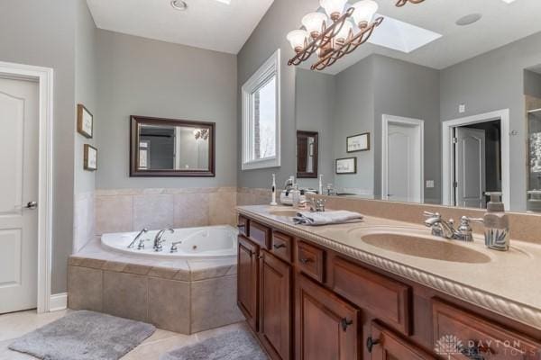 bathroom featuring a sink, a jetted tub, a skylight, and tile patterned floors