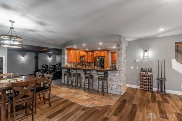 dining area featuring baseboards, wood finished floors, and ornate columns