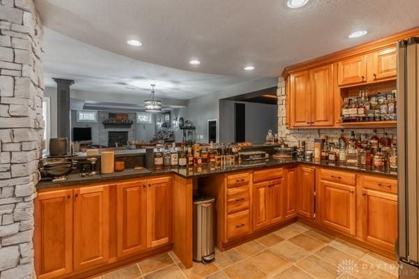 kitchen with decorative backsplash, brown cabinets, a peninsula, and a fireplace