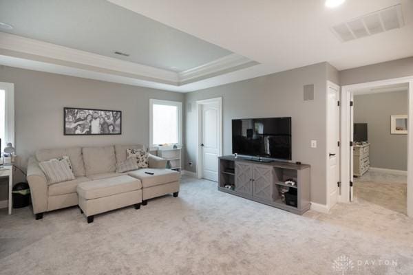 carpeted living area featuring a tray ceiling, visible vents, and baseboards