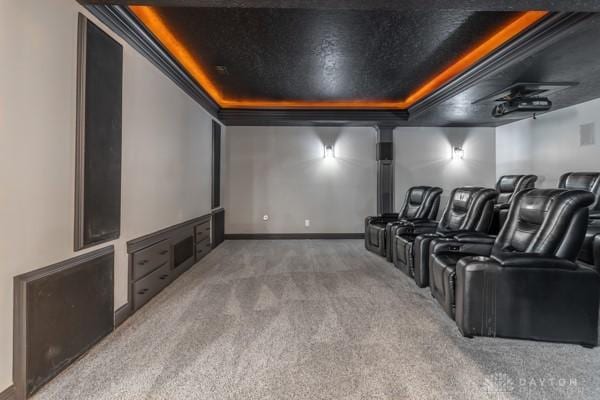 carpeted cinema room featuring a raised ceiling and baseboards