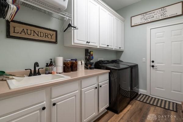 laundry room with a sink, cabinet space, wood finished floors, and washer and clothes dryer