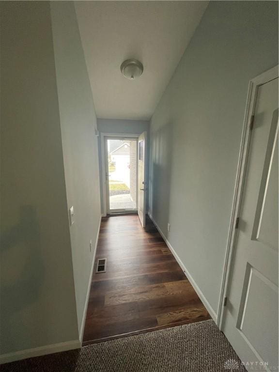 corridor with dark wood-style floors, visible vents, baseboards, and vaulted ceiling