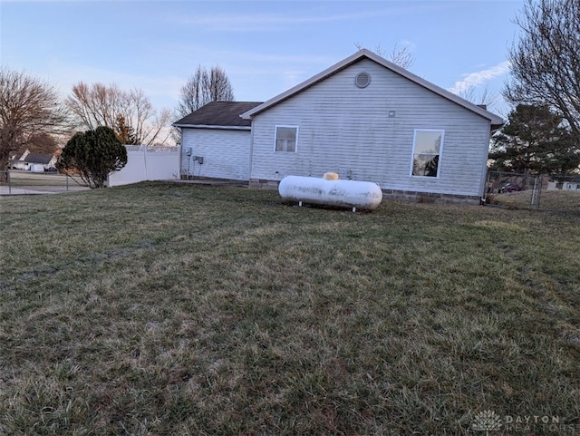 view of side of home featuring a lawn and fence