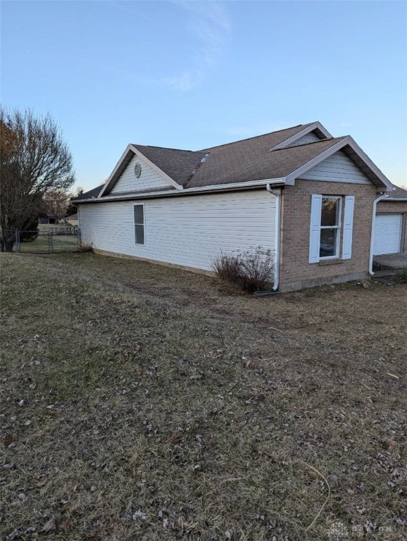 view of home's exterior featuring a yard, fence, and brick siding